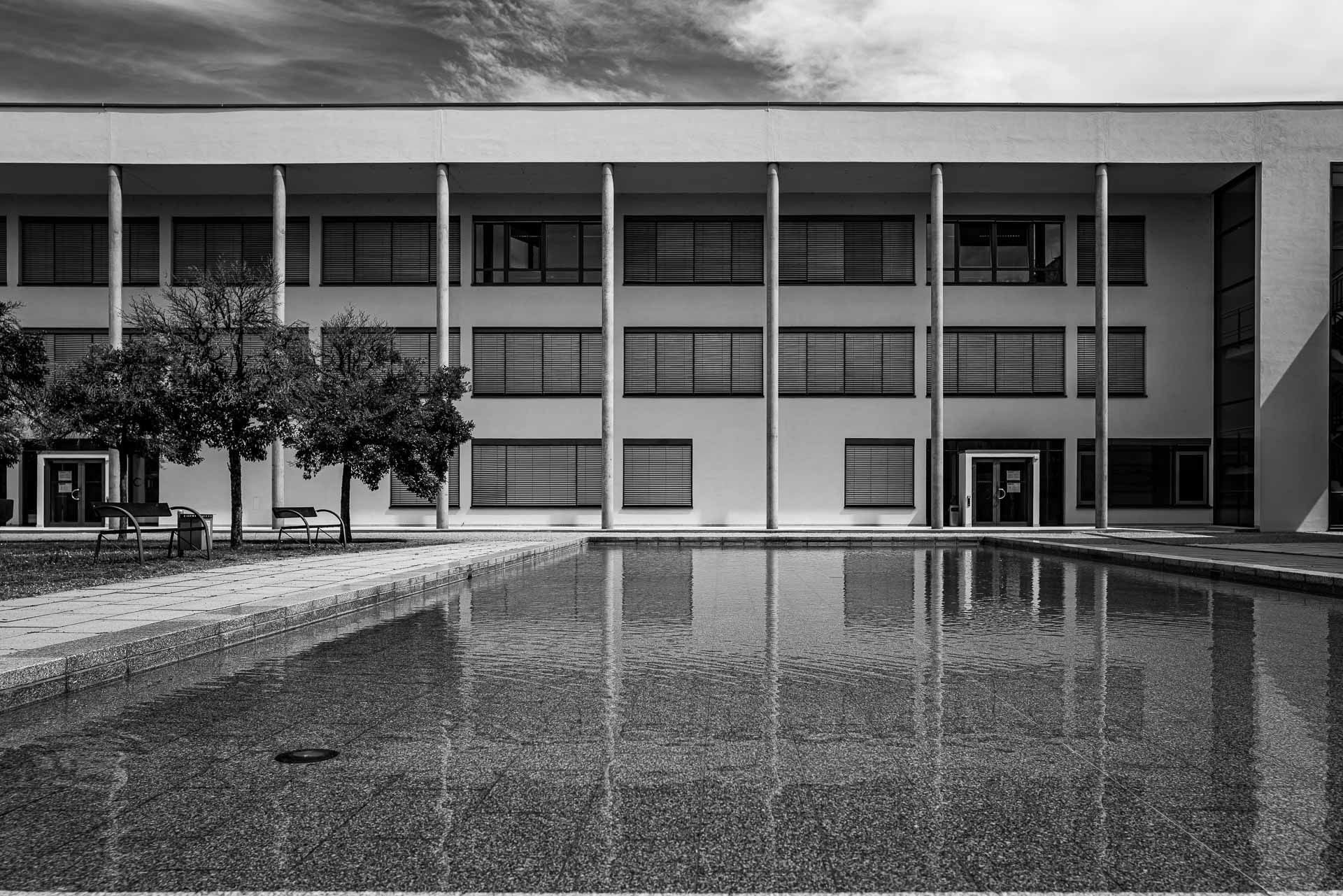 im Wasserbecken spiegeln sich die Säulen der Gebäudeüberdachung