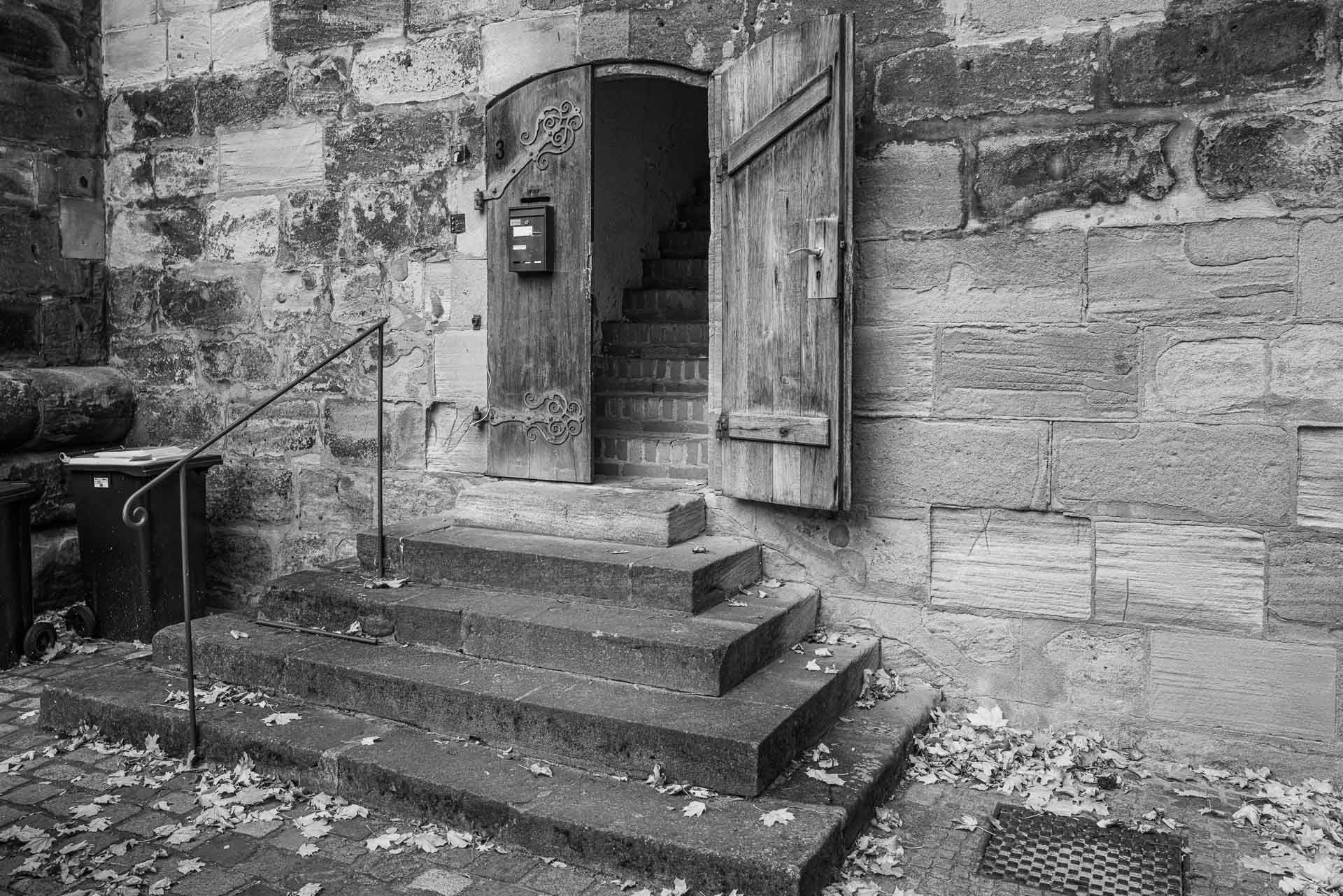das untere Ende der steilen Treppe mit halb geöffnetem Tor